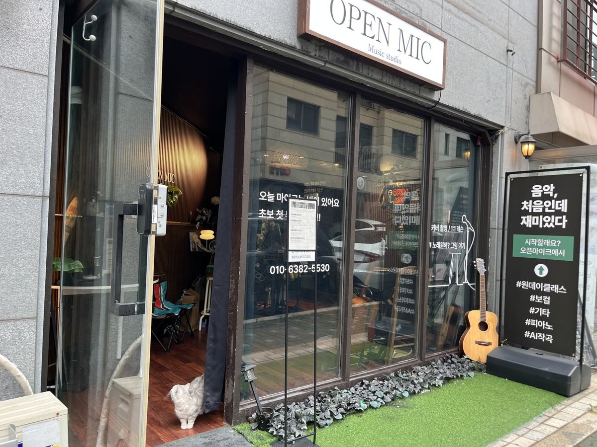 오픈믹 매장 외관, 유리문 앞 입간판과 고양이 키키